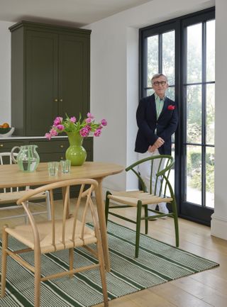 Jasper Conran in a dining room with green striped rug and hot pink flowers