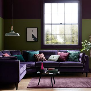 A purple and green living room with a dark purple corner sofa