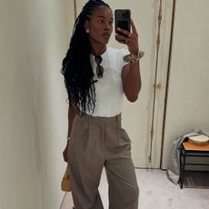 Influencer Marilyn wears a white tee and beige trousers. 