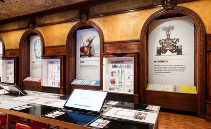 Design boards displayed within wooden, arched alcoves. A table in front displays screens and text about the company's design process