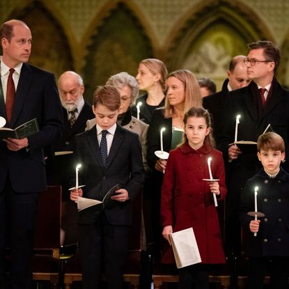 Prince William wears a suit and looks at his family, Prince George, Princess Charlotte, Prince Louis, and wife Kate Middleton who wears a white suit