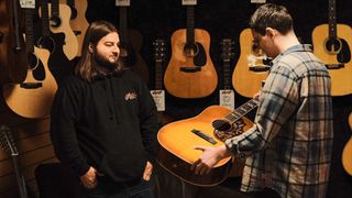 Sales assistant showing a customer an acoustic guitar in a guitar store