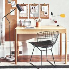 A home office set up with a desk and a chair and a floor lamp