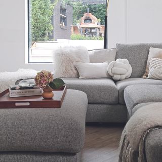 Living room with large grey l-shaped sofa and ottoman.