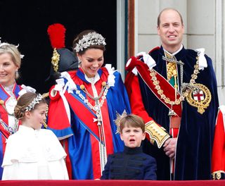 Prince Louis making a funny face on the palace balcony at King Charles's coronation as Princess Charlotte and Princess Kate look on and laugh and Prince William smiles in a gold-trimmed robe