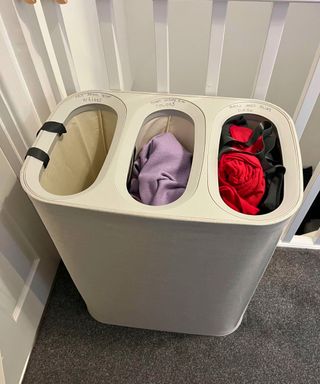 My laundry organizer from Joseph Joseph, showing three compartments and the one on the right with red and black laundry is full