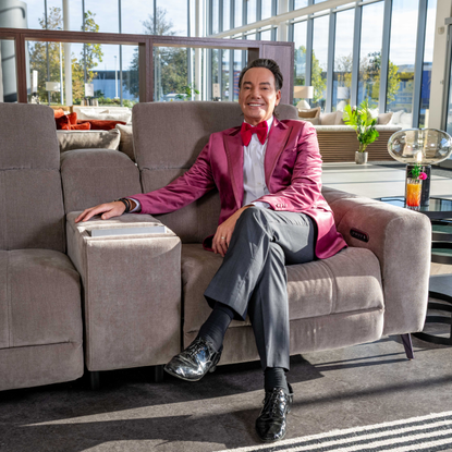 Craig Revel Horwood sat on a grey sofa in the Sofology show room.