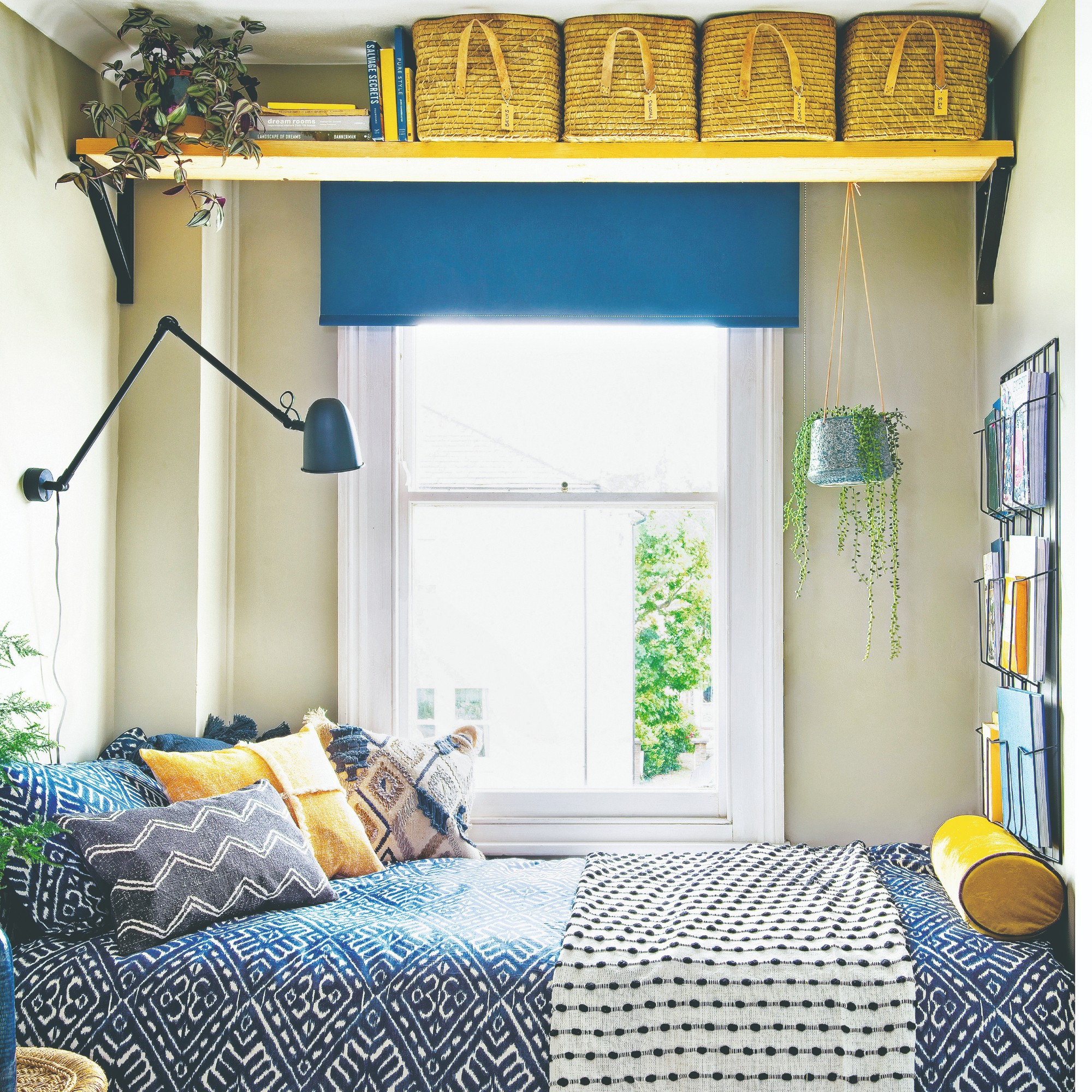 A pale green-painted box bedroom with above head storage and blue patterned bed linen