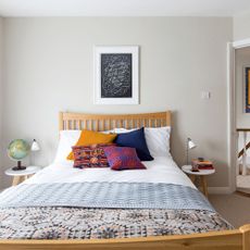Small grey bedroom with double bed, colourful cushions, side tables and picture on the wall