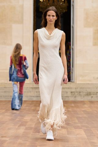 Model walking on the Gabriela Hearst runway wearing a fringed dress.