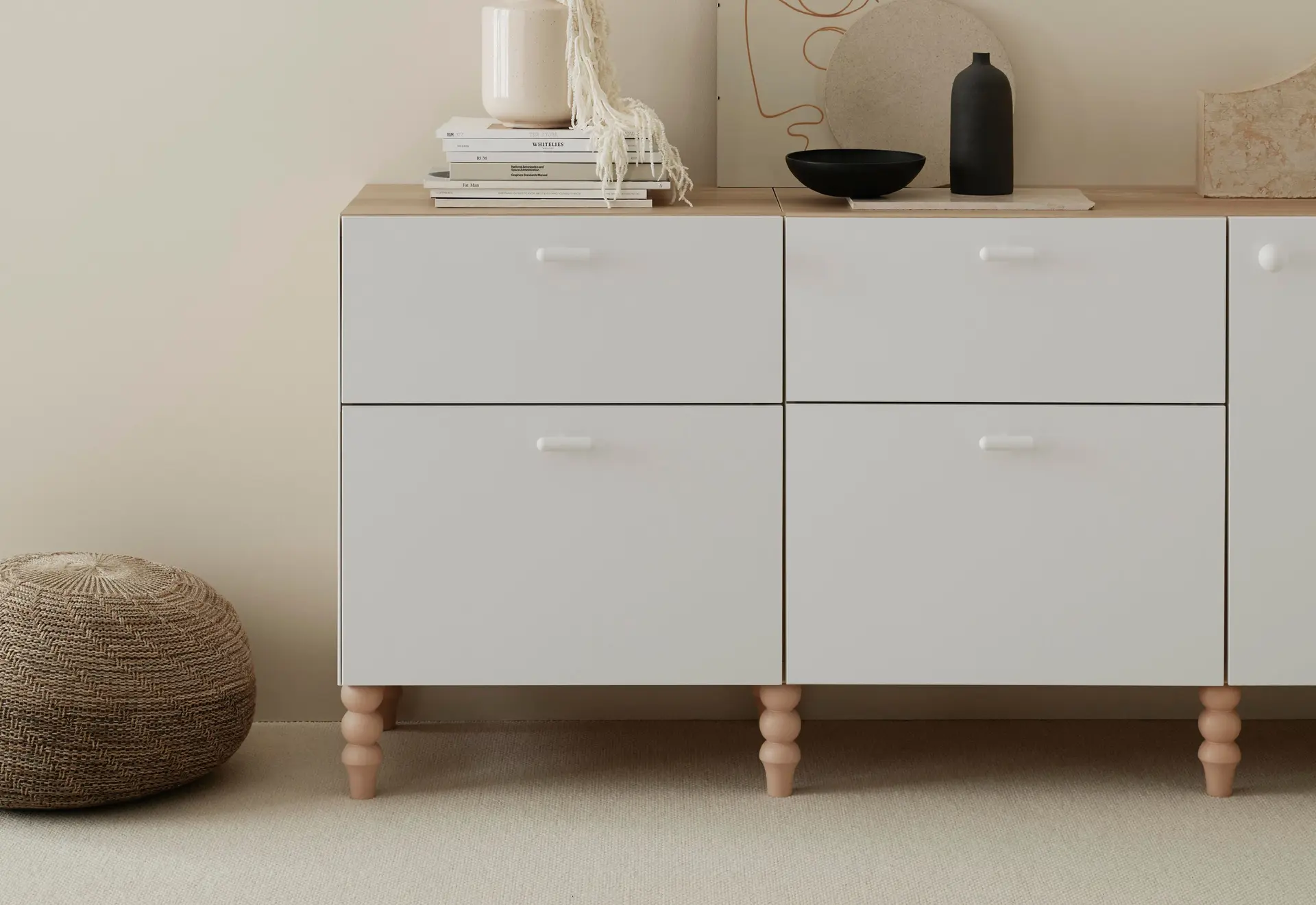 IKEA cabinet with Pretty Pegs custom legs, a jute ottoman, and styled with books, vases, and artwork