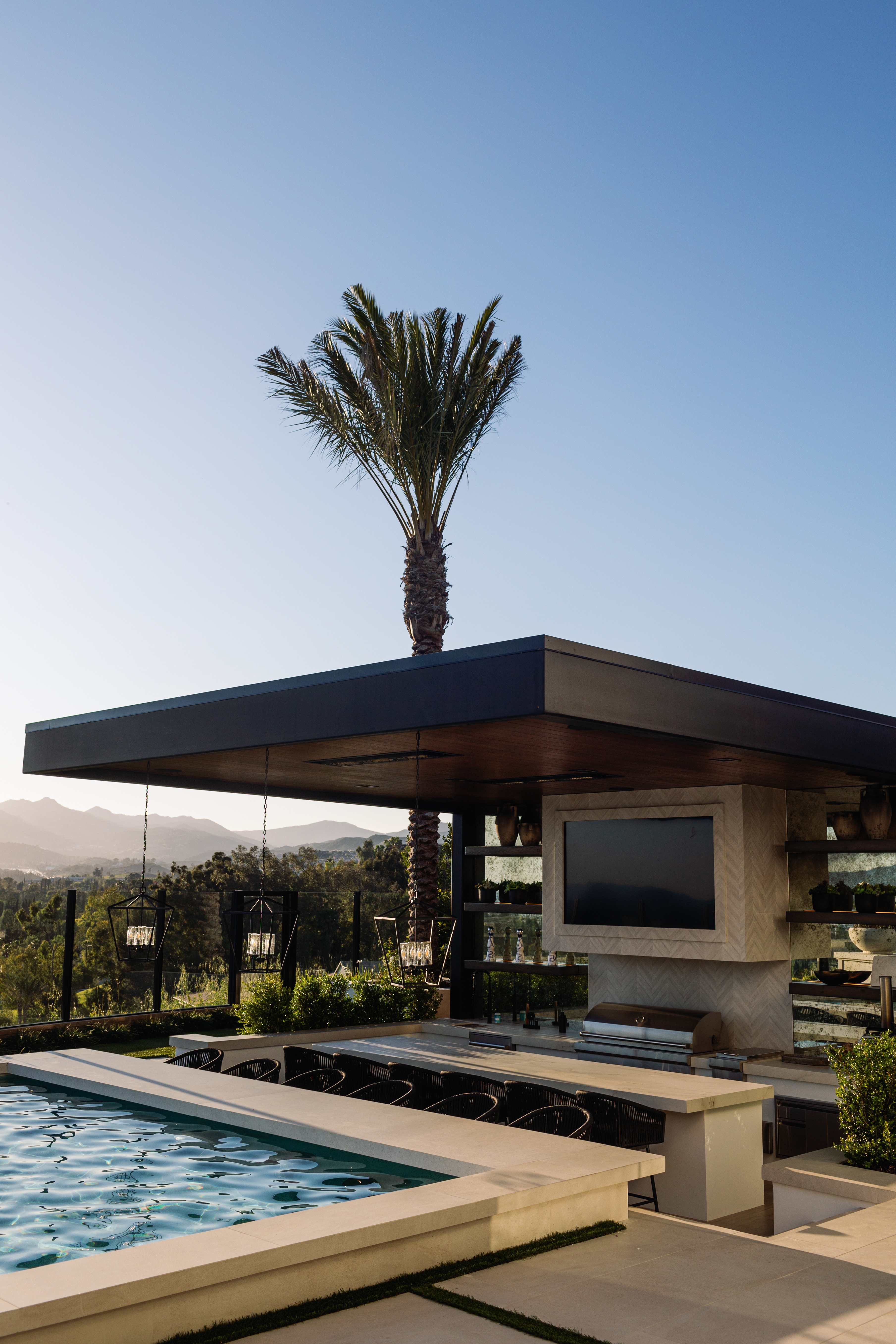 built in concrete outdoor kitchen and bar next to a pool