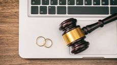 Wedding rings sit on top of a laptop keyboard along with a judge's gavel.