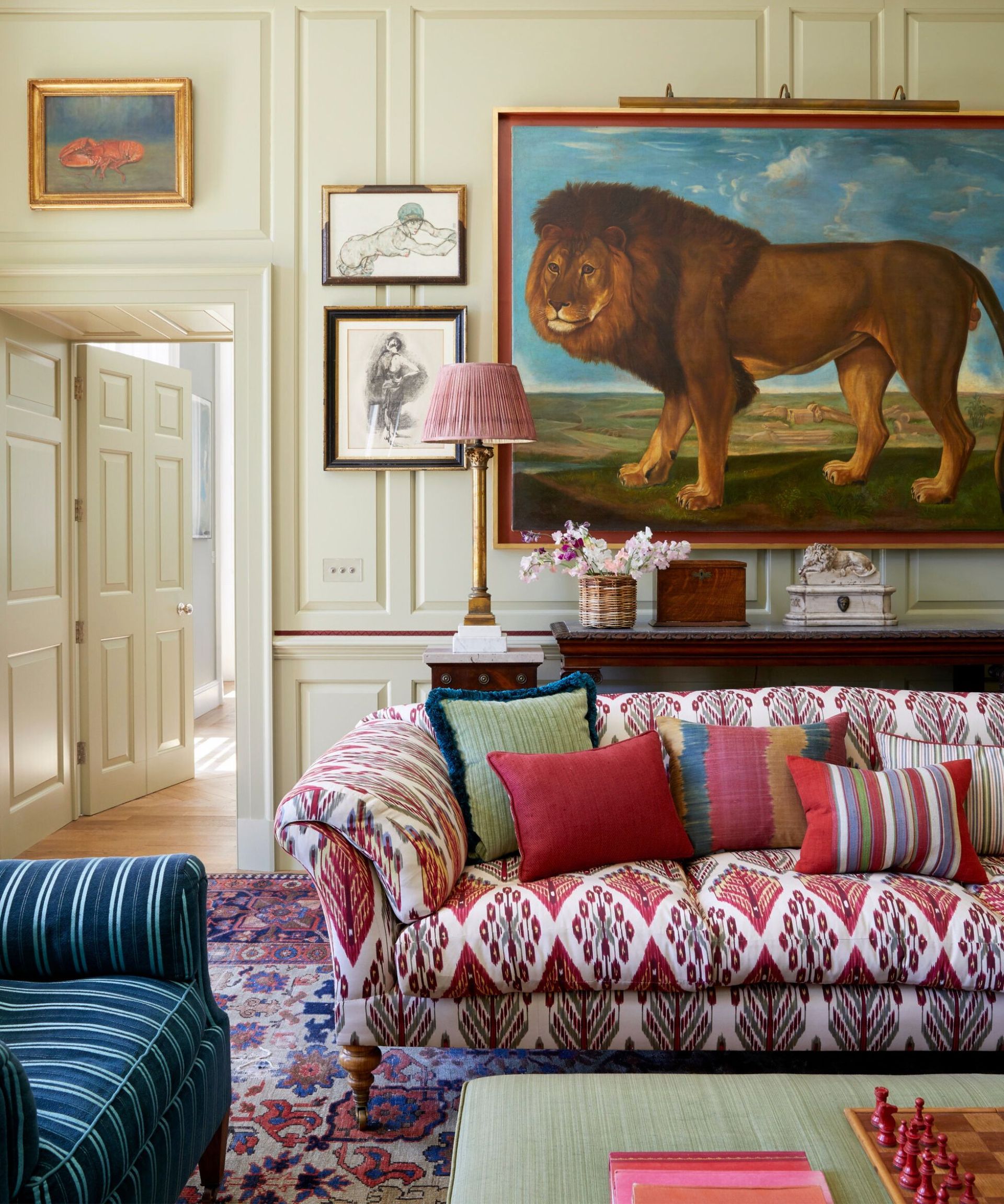 English country living room with a traditional patterned sofa and a large lion artwork. Interior by VSP Interiors, photograph Paul Massey