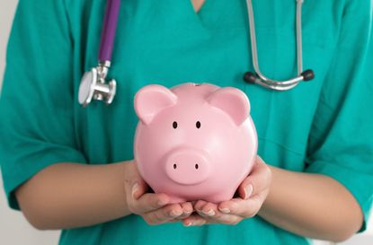 Female Doctor Holding Piggy Bank. Doctor's hands close-up. Medical insurance and health care concept.