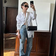 Alexis Badiyi taking a mirror selfie in a white button down with black sunglasses.