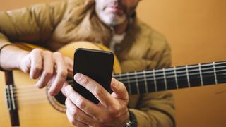 Guitar player uses his phone