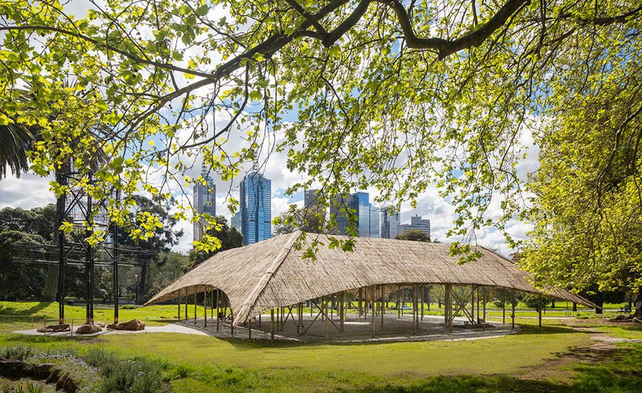 This year’s MPavilion by Bijoy Jain has just been launched in Melbroune’s Queen Victoria Gardens. An outdoor pavilion made of bamboo in a park with the city in the background.