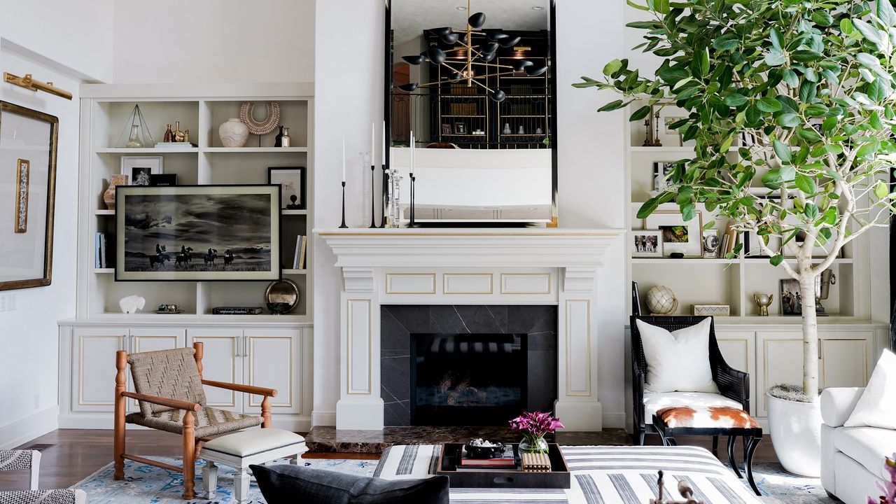 A family room with white walls, white fireplace, large mirror over the mantel, built-in shelves and brown and black armchairs