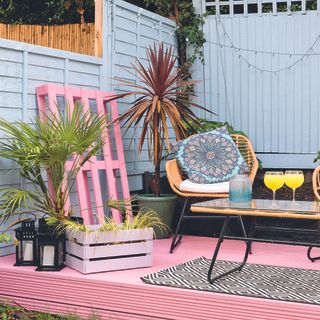 pink painted raised deck with blue painted fence and outdoor living area furniture
