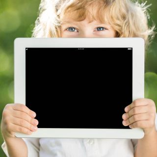 Child holding iPad in front of face