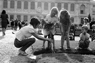 A black and white image of a young girl crying after getting wet from a fountain