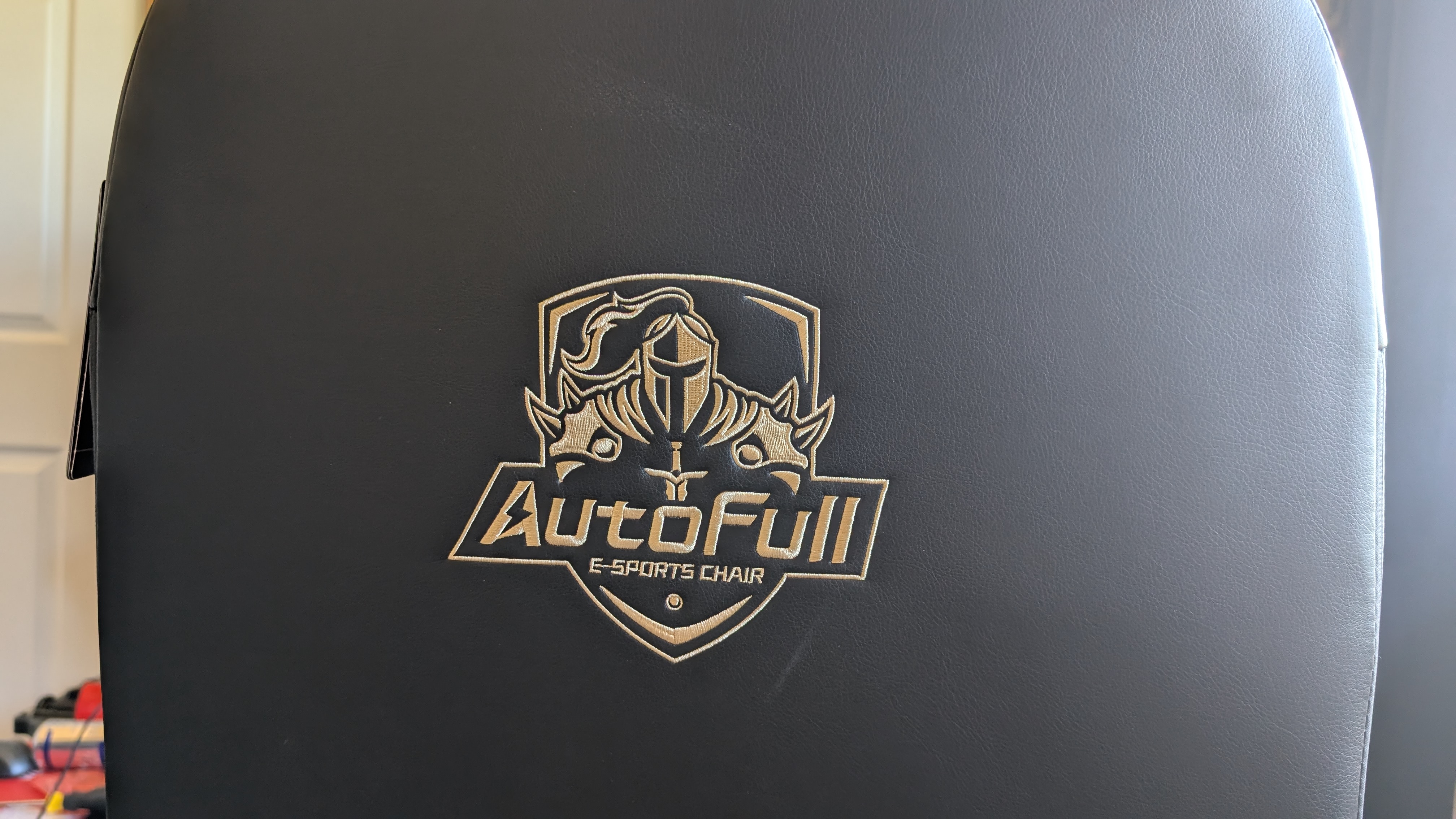 The AutoFull M6 Ultra gaming chair pictured in front of a desk with a gaming PC setup.