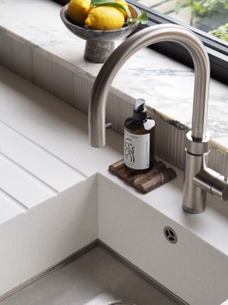 a close up of a kitchen sink with a marble window sill in the background