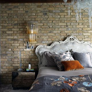 bedroom with brick walls and wooden bedside table
