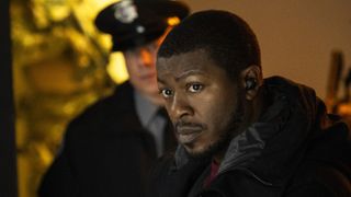 Edwin Hodge as Special Agent Ray Cannon standing in front of a cop in FBI: Most wanted season 5