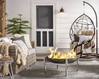 A hanging outdoor egg chair positioned next to a black round fire pit