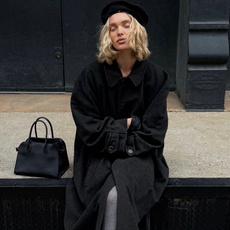 Model Elsa Hosk wears black court, black pillbox hat, and black gloves with grey tights and black court shoes.
