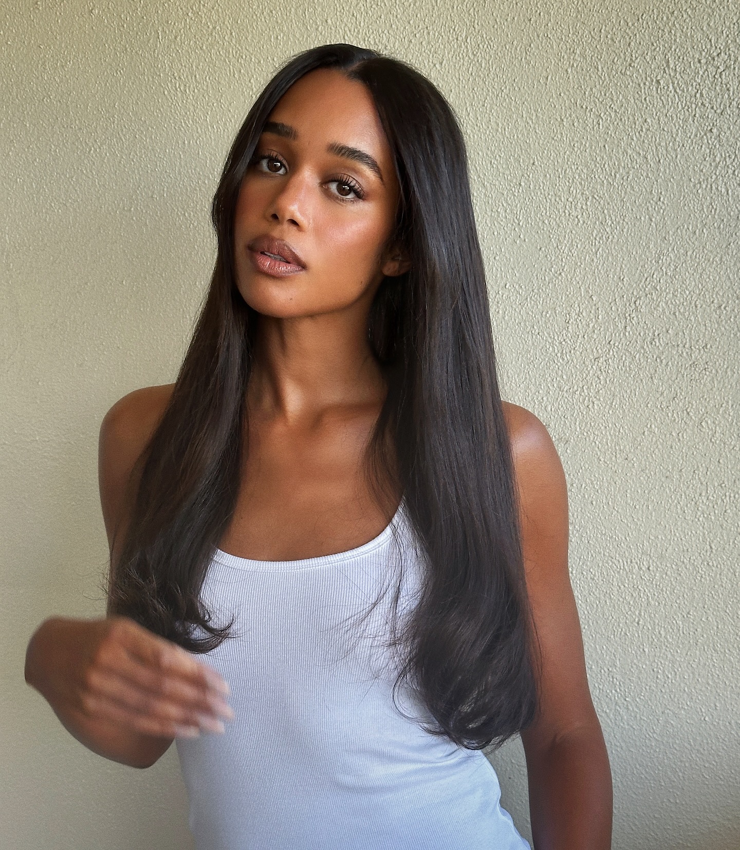 Laura Harrier wearing white tank with long fluttery lashes