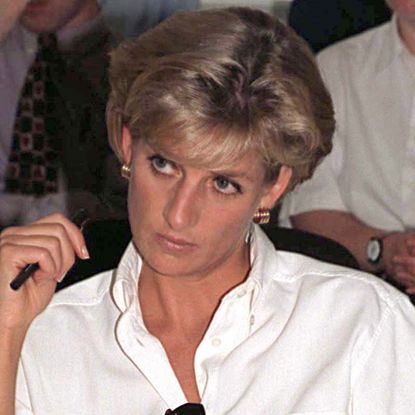 Princess Diana wears a white button-down shirt and looks pensive