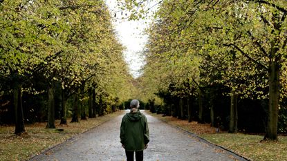 Senior woman standing on footpath amidst autumn trees