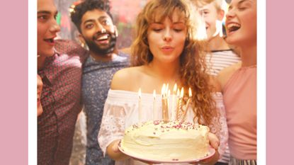 Woman blowing candles while celebrating birthday with friends