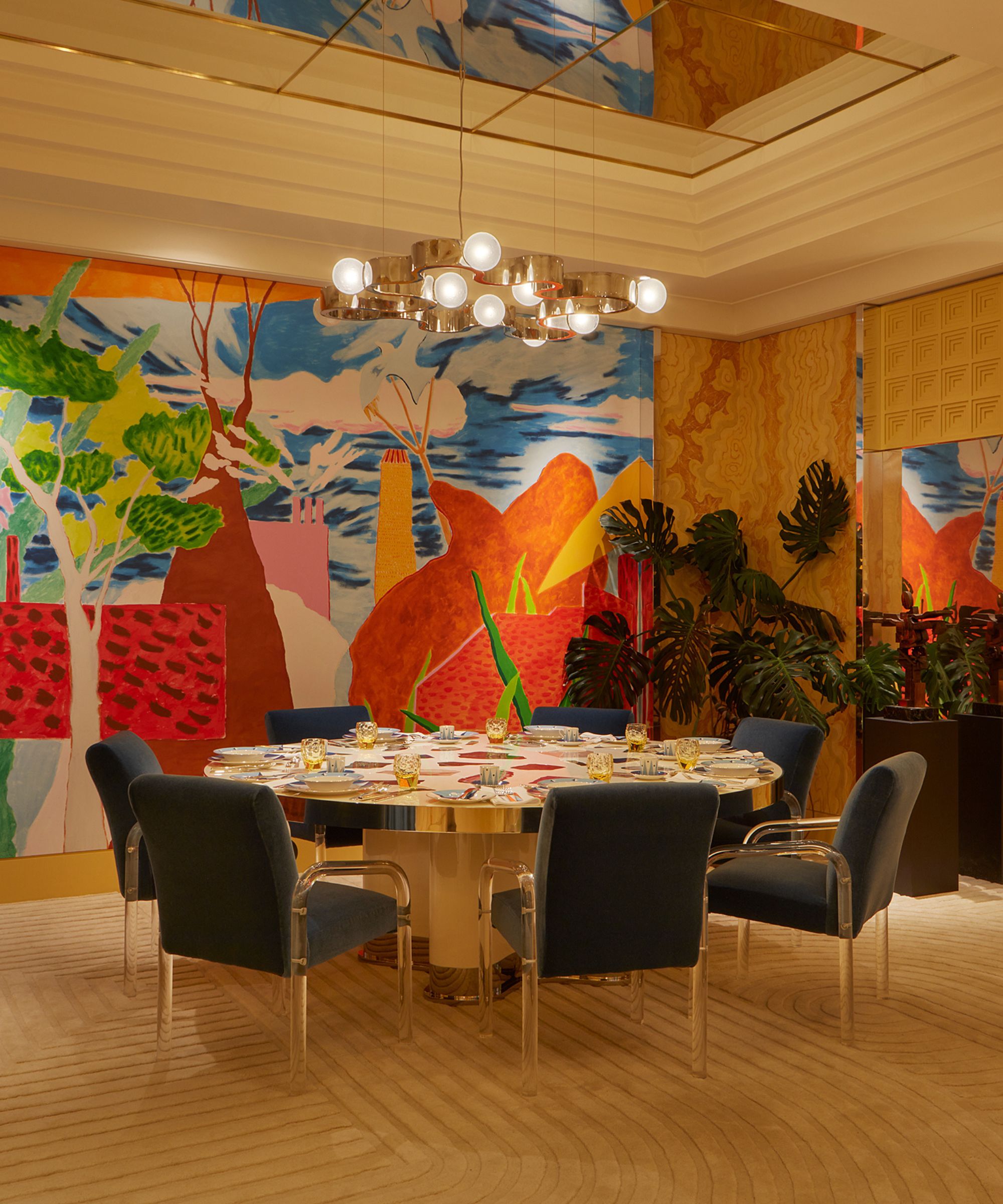 A large dining room with a colorful abstract wall mural and a dining table with blue dining chairs