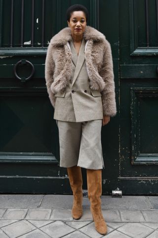 woman wearing a faux fur coat, blazer, bermuda shorts, boots