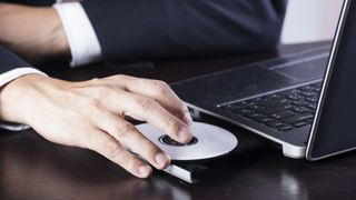 Man slotting in disc into laptop