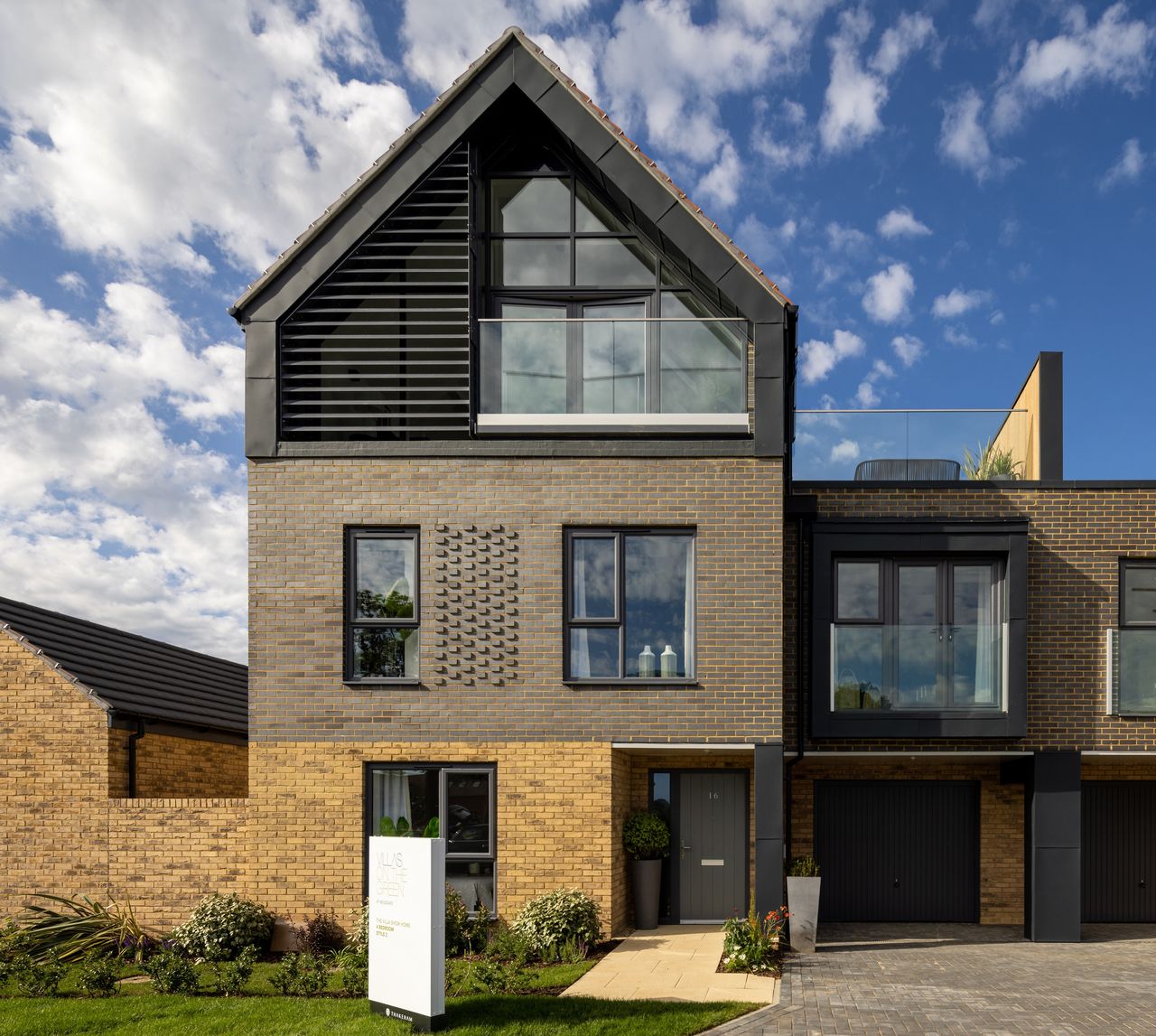 A exterior shot of a three storey Scandinavian inspired house built of brick with a third floor balcony