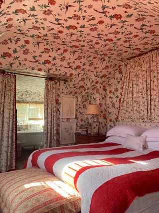 Bedroom with wallpaper across the ceiling and curtains used as doors