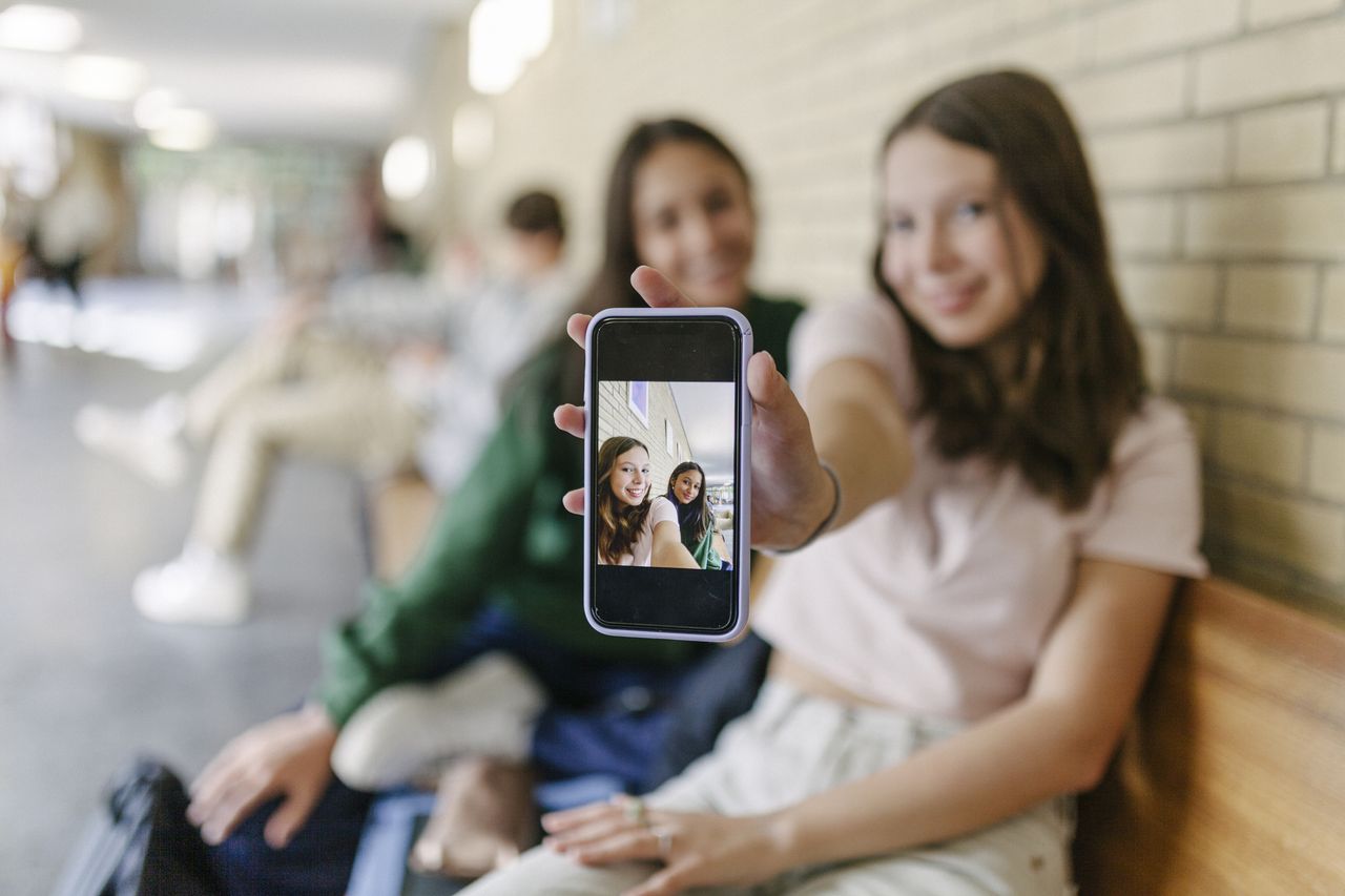 A high school student showing a selfie of her and a friend to the camera.