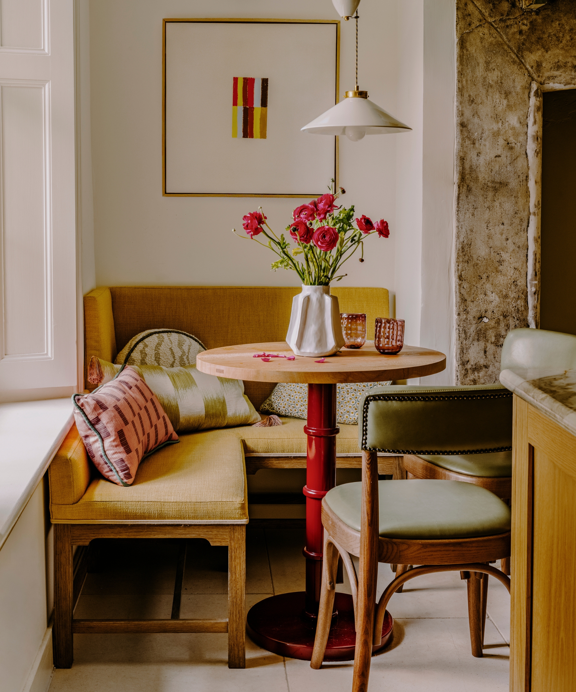 A small dinette in the corner of a kitchen with yellow upholstery and wooden chairs