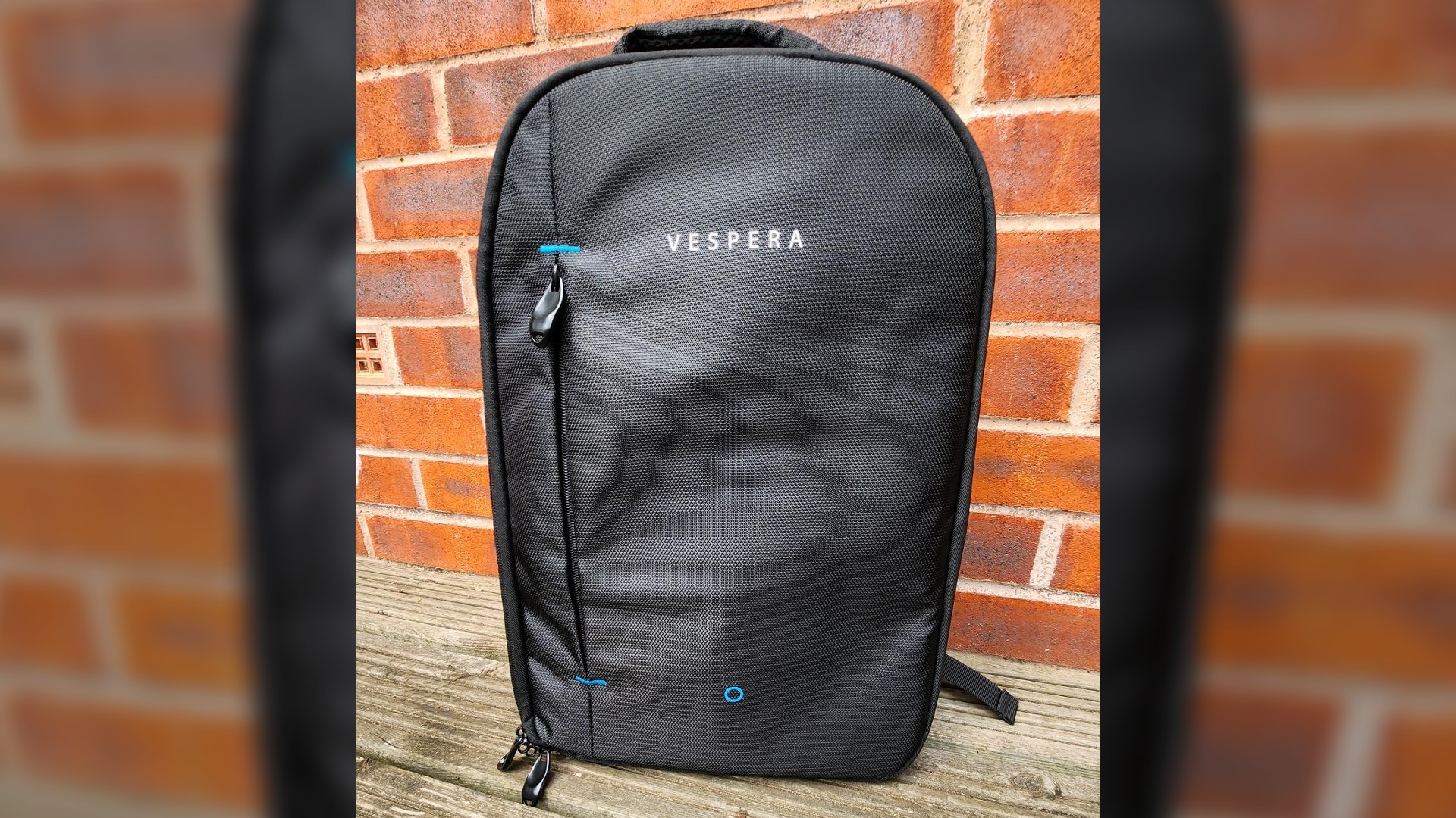 A sleek black backpack that contains the Vaonis Vespera Observation Station. There is a main zipper all the way around. There is a secondary pocket at the front, with Vespera written on it in white text. There is a black handle on the top.