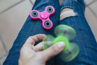 A girl playing with two fidget spinners.