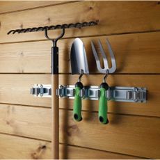 Garden tool holder storing tools in shed