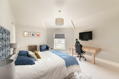 A bedroom in a semi circle shape with a TV opposite the bed