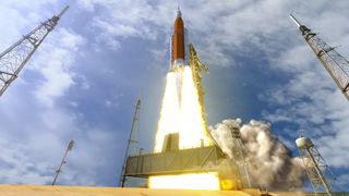 artemis 1 rocket blasting off from launch pad surrounded by lightning towers