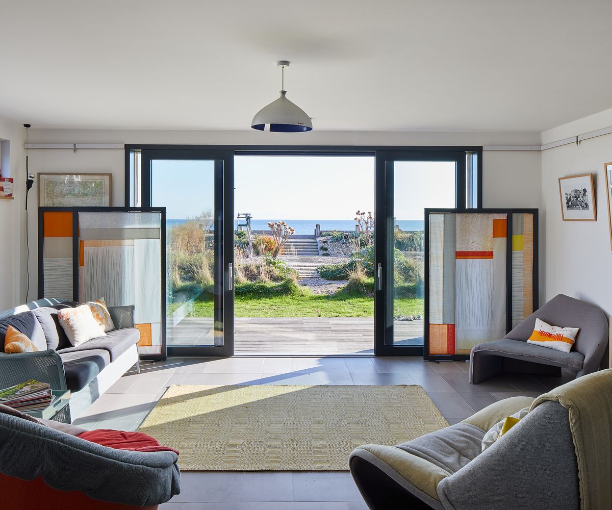 a cosy living space with rugs and bold cushions with sliding glass door opening onto decking