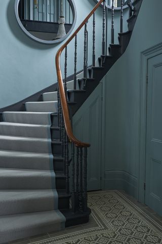 grey stair runner in blue entryway with patterned tiled flooring by Bert & May
